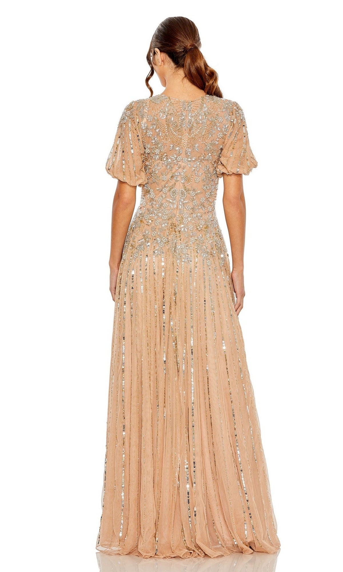 A woman faces away, wearing the Mac Duggal 5991 Short Sleeve Beaded Formal Dress—a floor-length, nude gown adorned with silver sequins.